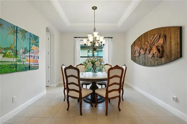 Dining space with a chandelier, arched walkways, and a raised ceiling
