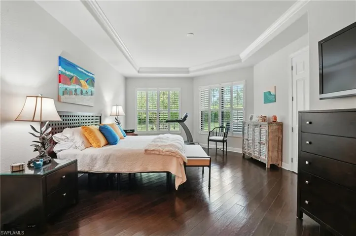 Bedroom featuring a tray ceiling and wood-type flooring