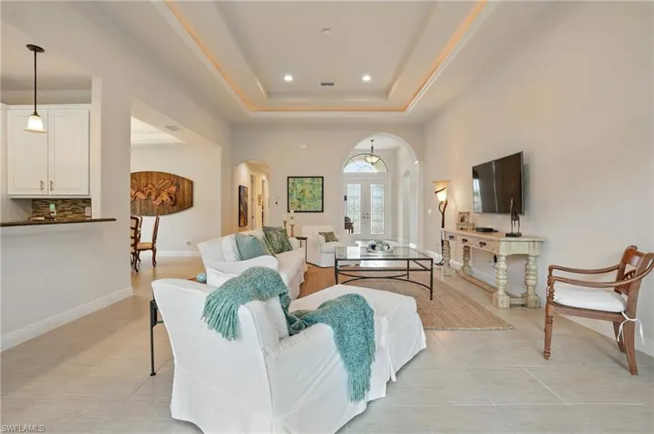 Living area with arched walkways, recessed lighting, a tray ceiling, and light tile patterned floors