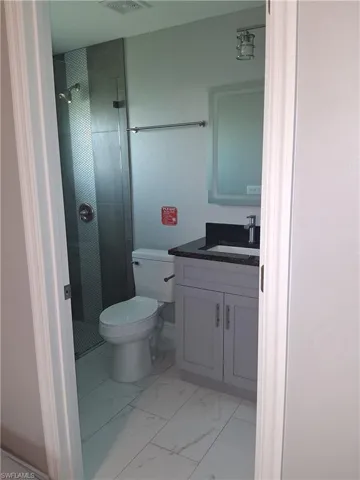 Bathroom featuring vanity, a stall shower, and light marble finish floors