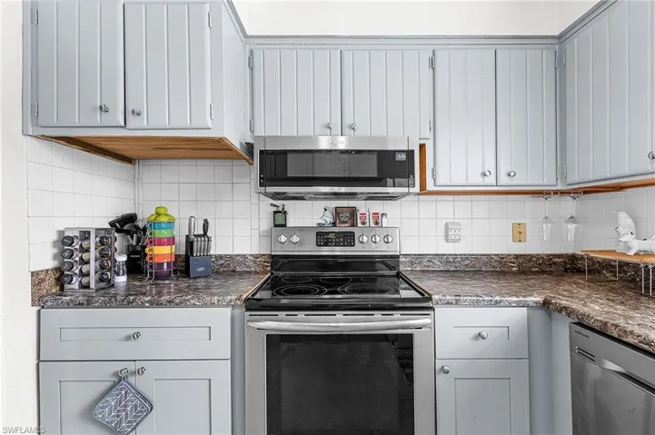 Kitchen with dark countertops, appliances with stainless steel finishes, and decorative backsplash