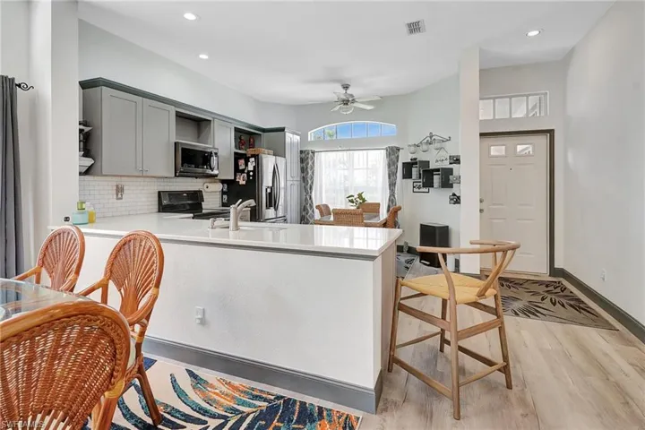 Kitchen featuring kitchen peninsula, ceiling fan, light hardwood / wood-style flooring, and stainless steel appliances
