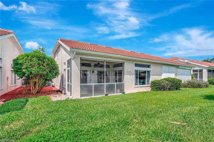 Rear view of property with ceiling fan, a sunroom, and a yard