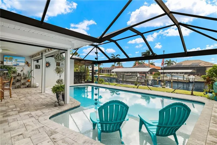 View of swimming pool featuring a water view, a patio area, and glass enclosure