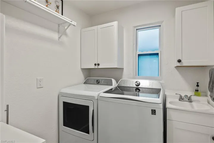 Clothes washing area with washer and dryer, cabinets, and sink