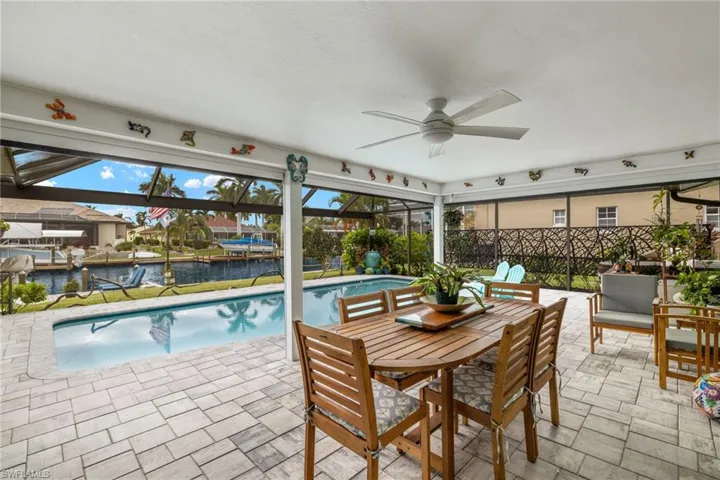 View of swimming pool featuring a water view, ceiling fan, and a patio