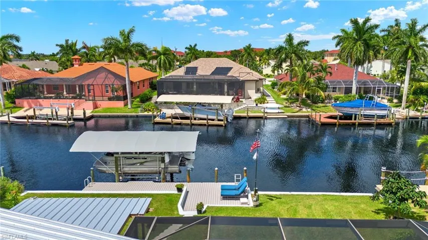 View of dock with glass enclosure, a lawn, and a water view