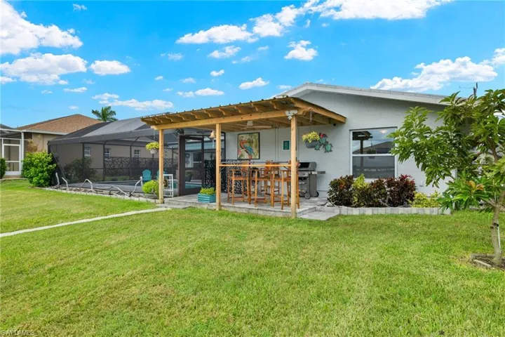 Rear view of property with a yard, a patio, glass enclosure, and a pool