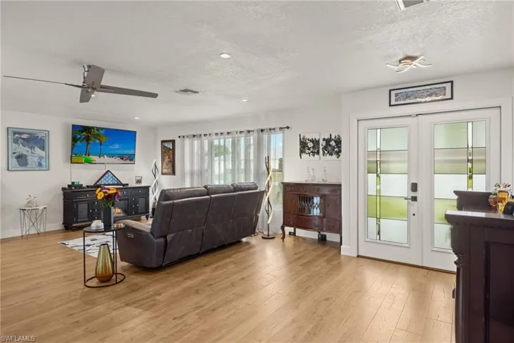 Living room featuring french doors, ceiling fan, a textured ceiling, and light hardwood / wood-style flooring