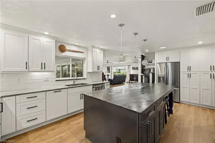 Kitchen with white cabinetry, tasteful backsplash, sink, appliances with stainless steel finishes, and light hardwood / wood-style floors