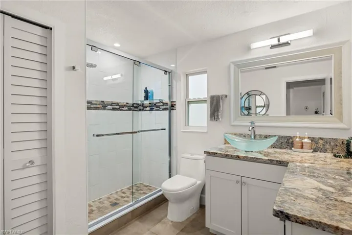 Bathroom with vanity, toilet, and an enclosed shower