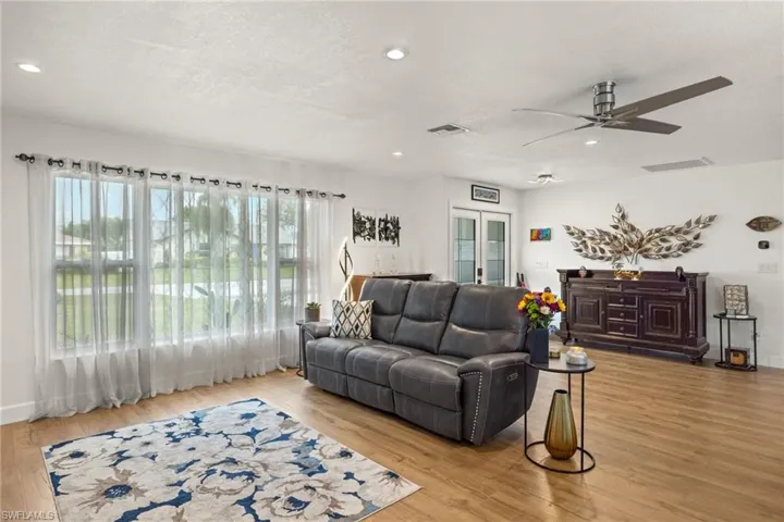 Living room with light wood-type flooring, ceiling fan, a textured ceiling, and french doors