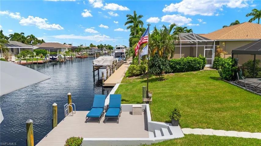 View of dock featuring a lanai, a water view, and a lawn