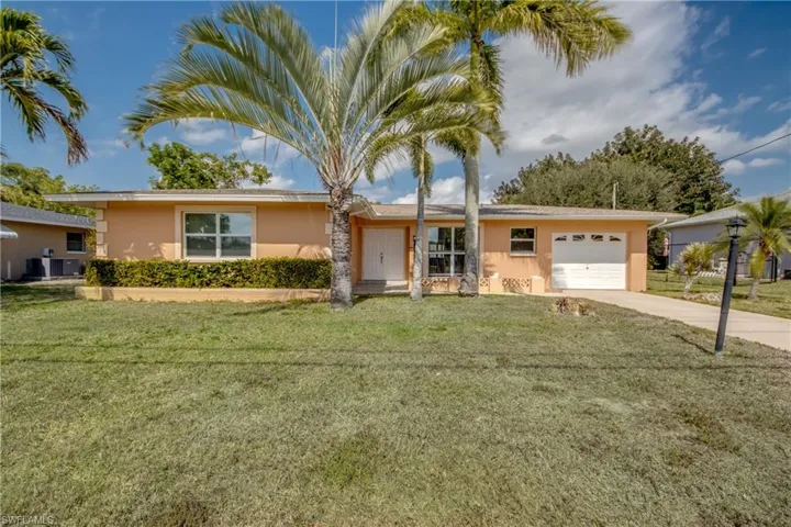 Ranch-style house with stucco siding, a garage, concrete driveway, and a front lawn
