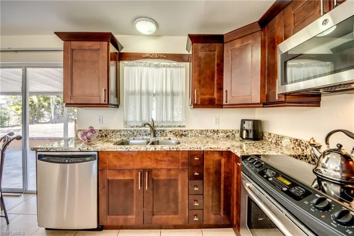 Kitchen featuring stainless steel appliances, light stone countertops, and plenty of natural light