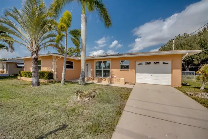 Single story home featuring stucco siding, a garage, and driveway