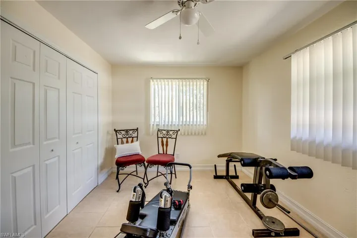 Workout area featuring a ceiling fan and light tile patterned floors
