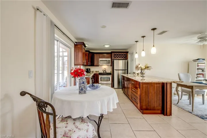 Kitchen featuring stainless steel appliances, light stone counters, decorative light fixtures, light tile patterned flooring, and a center island