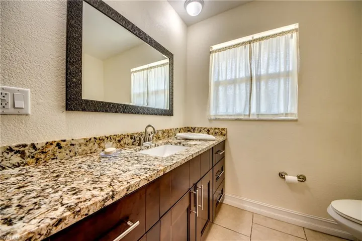 Bathroom featuring a textured wall, vanity, and light tile patterned floors