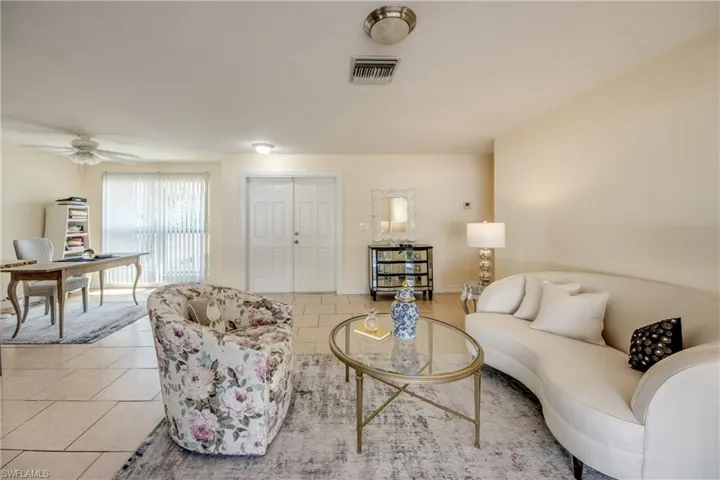 Tiled living room with a ceiling fan and baseboards