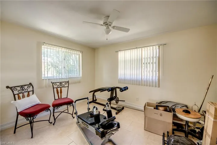 Exercise area featuring healthy amount of natural light, a ceiling fan, and light tile patterned flooring