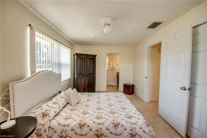 Bedroom with light tile patterned floors, ceiling fan, and ensuite bathroom