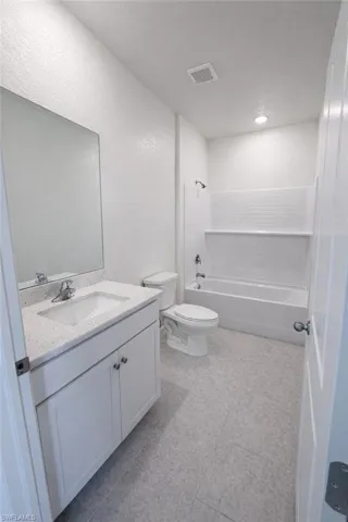 Full bath with vanity,  shower combination, a textured wall, and a textured ceiling