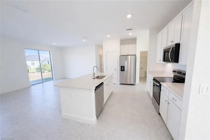Kitchen featuring stainless steel appliances, white cabinets, a center island with sink, recessed lighting, and open floor plan