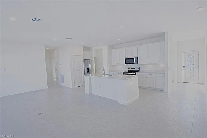 Kitchen featuring white cabinetry, stainless steel appliances, a kitchen island with sink, recessed lighting, and light stone countertops
