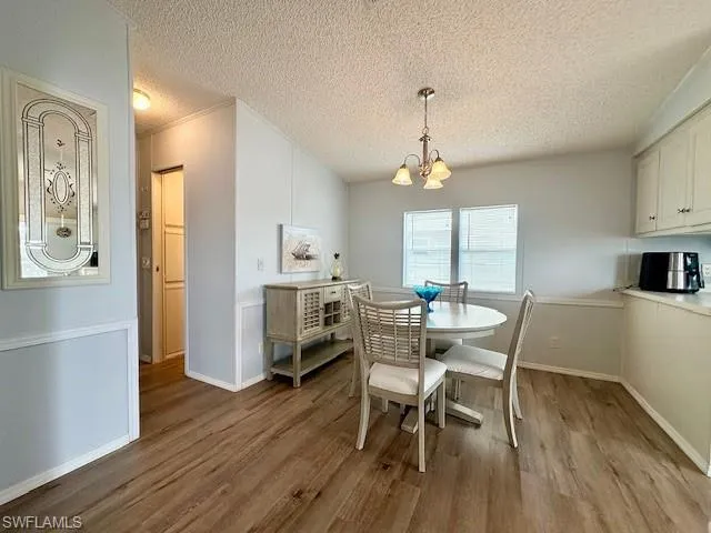 Dining space with hardwood / wood-style floors, a chandelier, and a textured ceiling