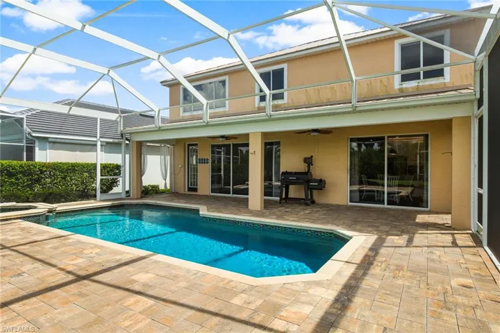 View of pool with glass enclosure, a patio area, ceiling fan, and area for grilling