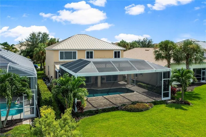 Back of house featuring glass enclosure, a yard, and a patio area