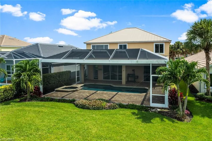 Rear view of property featuring a patio area, a lawn, and a lanai