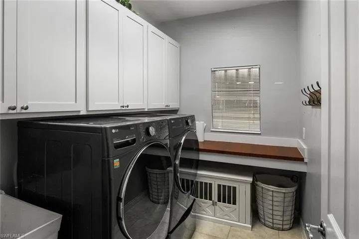 Washroom featuring independent washer and dryer, cabinets, and light tile patterned floors