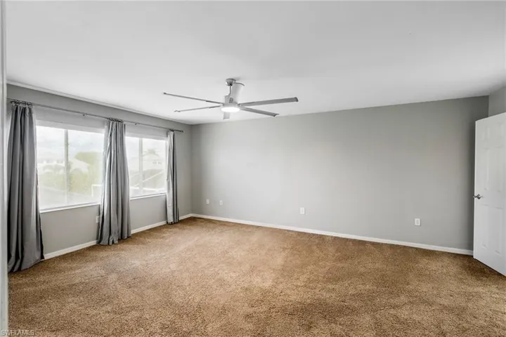 Empty room featuring ceiling fan and carpet flooring