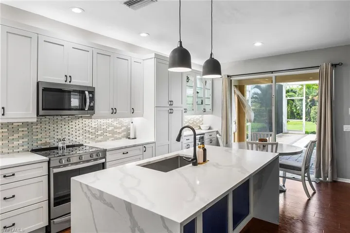 Kitchen featuring light stone countertops, stainless steel appliances, sink, dark hardwood / wood-style floors, and a center island with sink