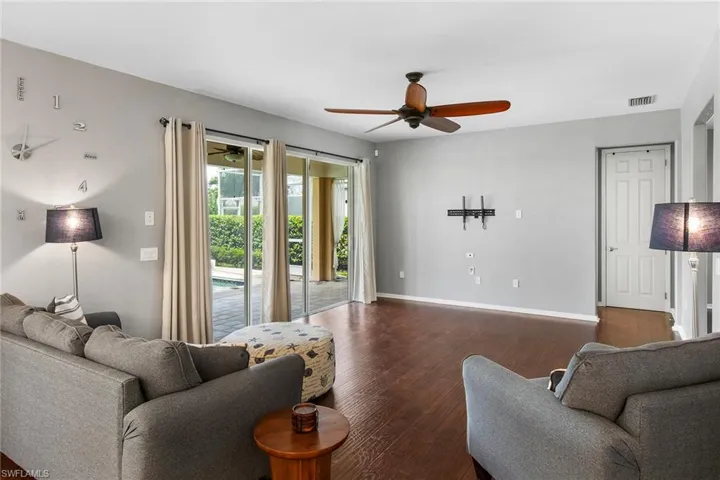 Living room with dark hardwood / wood-style flooring and ceiling fan