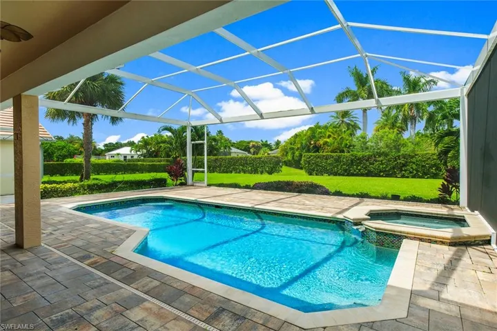 View of pool with a lanai, a patio area, a yard, and an in ground hot tub