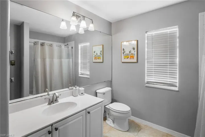 Bathroom featuring curtained shower, tile patterned flooring, toilet, and vanity