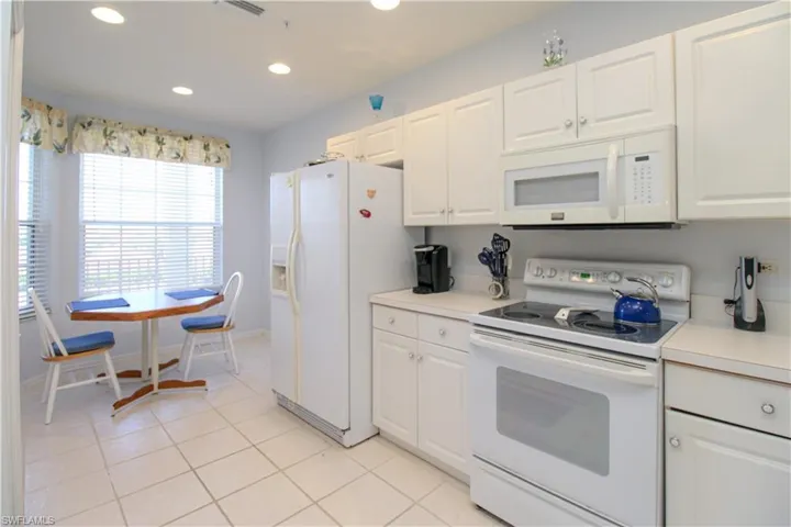 Kitchen featuring white cabinetry, white appliances, and light tile patterned floors