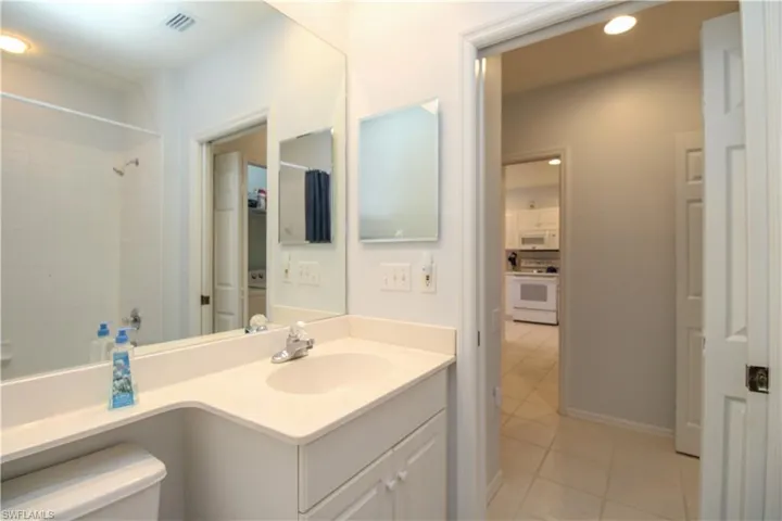 Bathroom with tile patterned flooring, a tile shower, vanity, and toilet