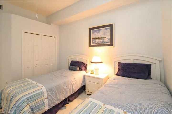Bedroom with light colored carpet and a closet