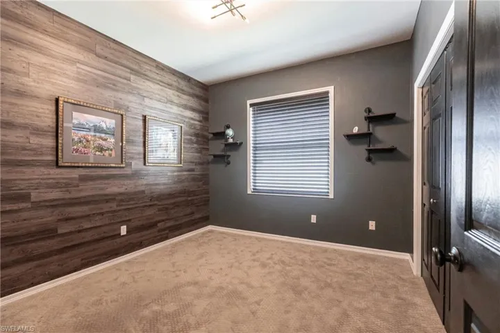 Carpeted empty room with a chandelier and wooden walls