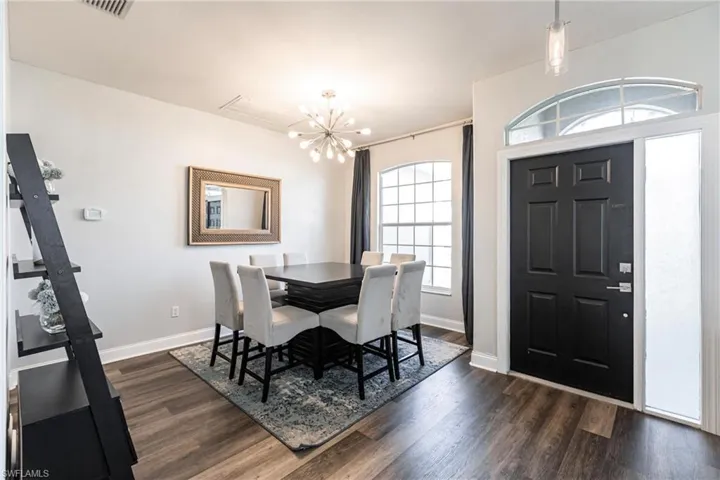 Dining room with a notable chandelier and dark wood-type flooring