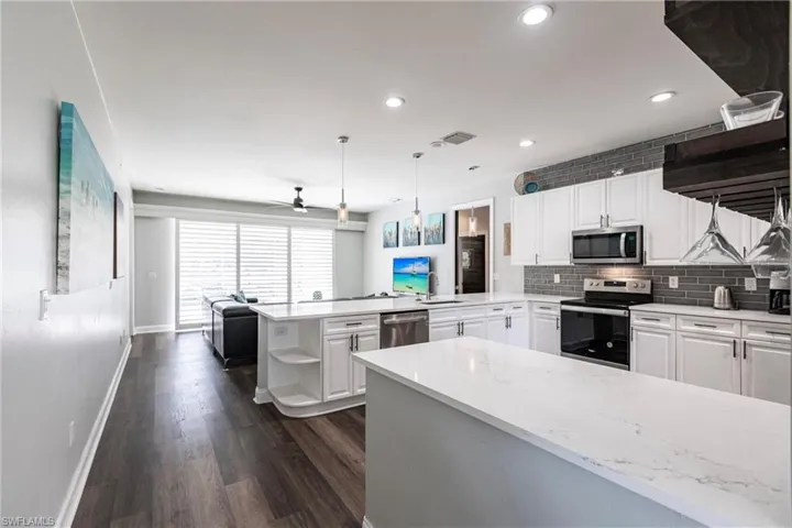 Kitchen with kitchen peninsula, hanging light fixtures, ceiling fan, white cabinetry, and stainless steel appliances