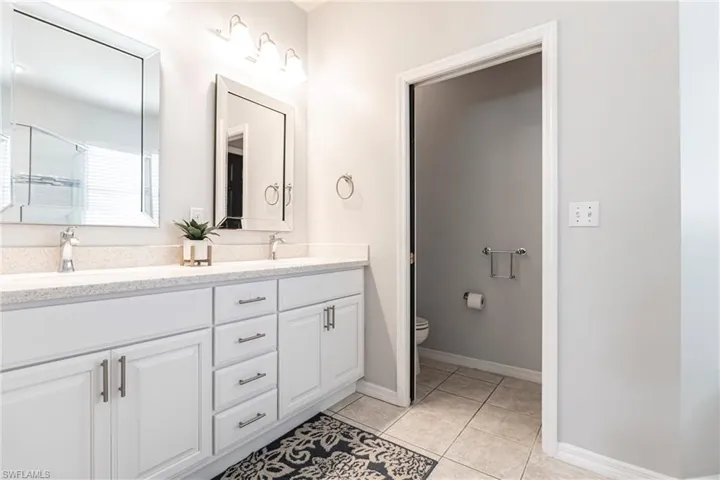 Bathroom with toilet, vanity, tile patterned floors, and a shower with shower door