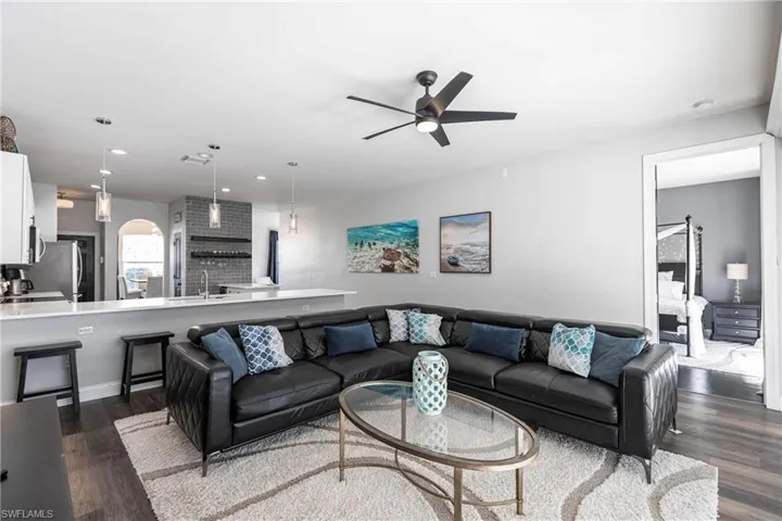 Living room with ceiling fan, dark hardwood / wood-style flooring, and sink