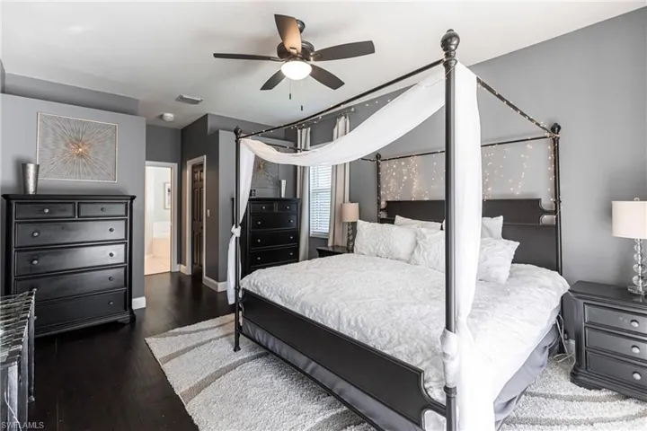Bedroom with ensuite bath, ceiling fan, and dark wood-type flooring