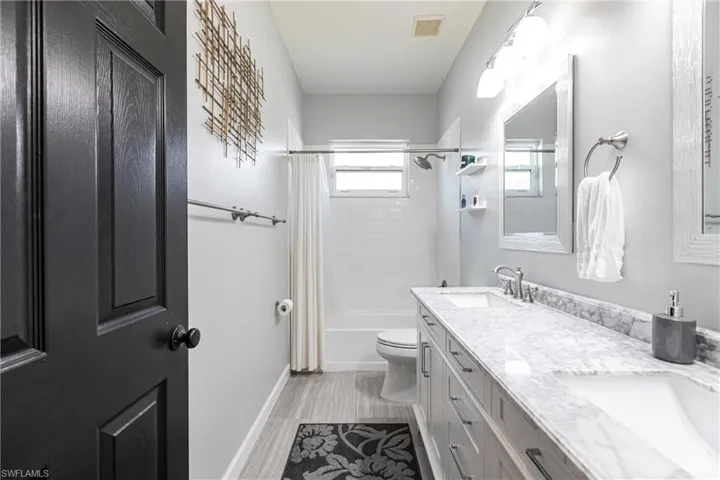 Full bathroom with shower / tub combo with curtain, vanity, and toilet