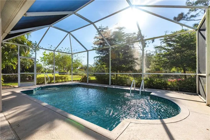 View of pool with glass enclosure and a patio area